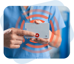 Healthcare - BadgeR+ - Mockup - Posed - Female Nurse in Light Blue Scrubs Pressing Activation Button and Orange Signals Coming Off Device